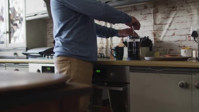 高加索人的中段在家厨房里准备咖啡