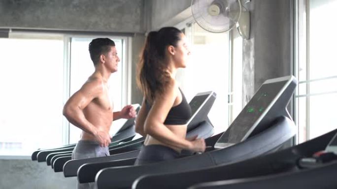男女在健身中心的跑步机上跑步。