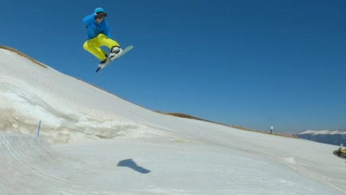 慢动作: 男性滑雪者在雪地公园的跳跃中表演时尚的抓斗技巧