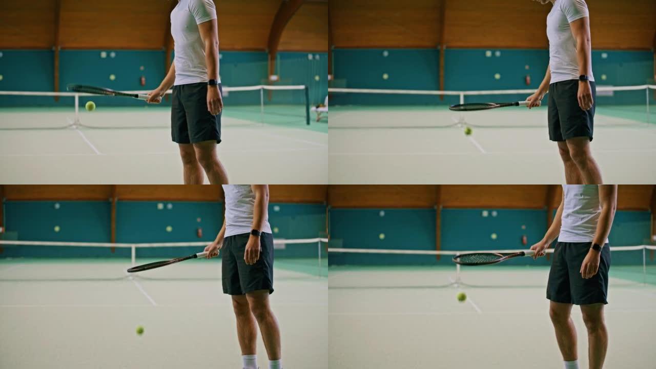 年轻的男教练穿着网球服弹跳球，地板上有球拍