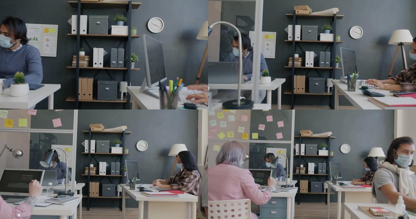 在办公室戴口罩的员工在办公桌上使用计算机