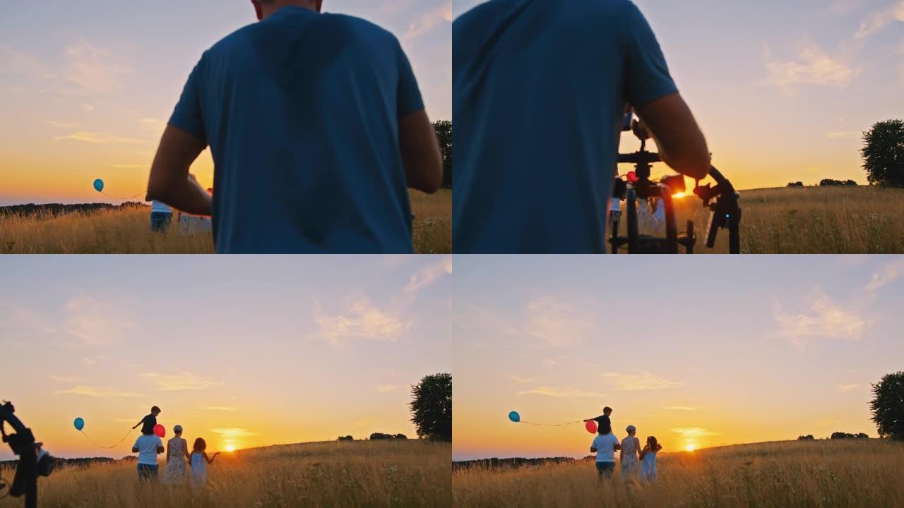 一名摄影师在草地上走向日落时拍摄四口之家的慢动作轨道镜头