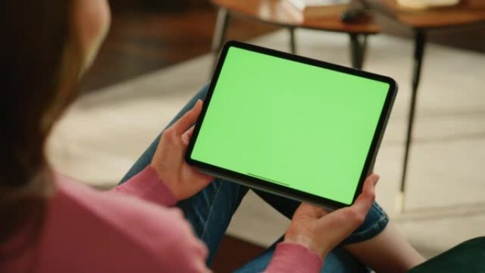 女性进行视频通话，手持平板电脑，绿屏模拟显示。在家工作时，专家会赶上同事。女人在移动设备上与朋友交谈