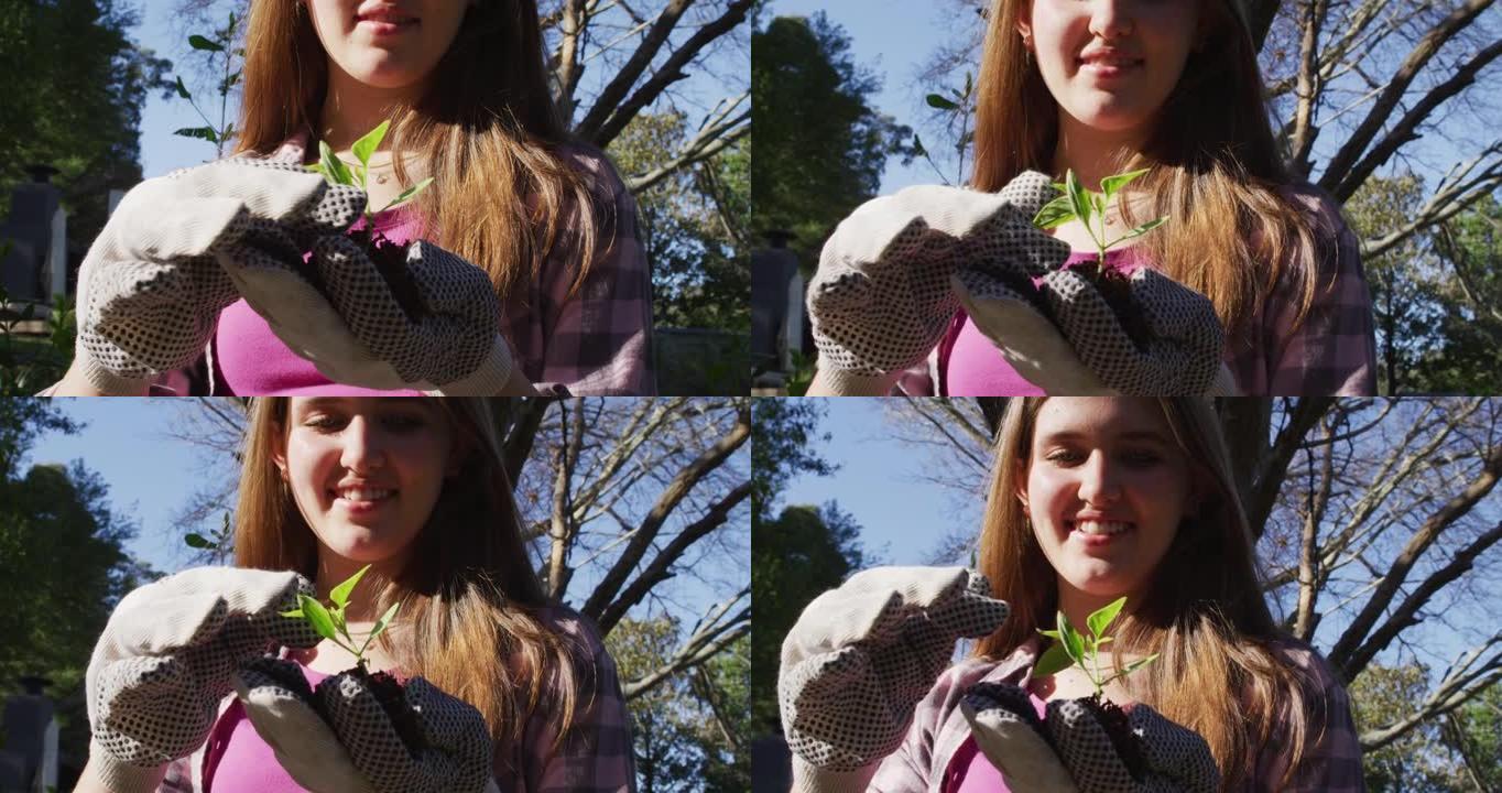 微笑的高加索少女在花园里工作，戴着手套并检查植物