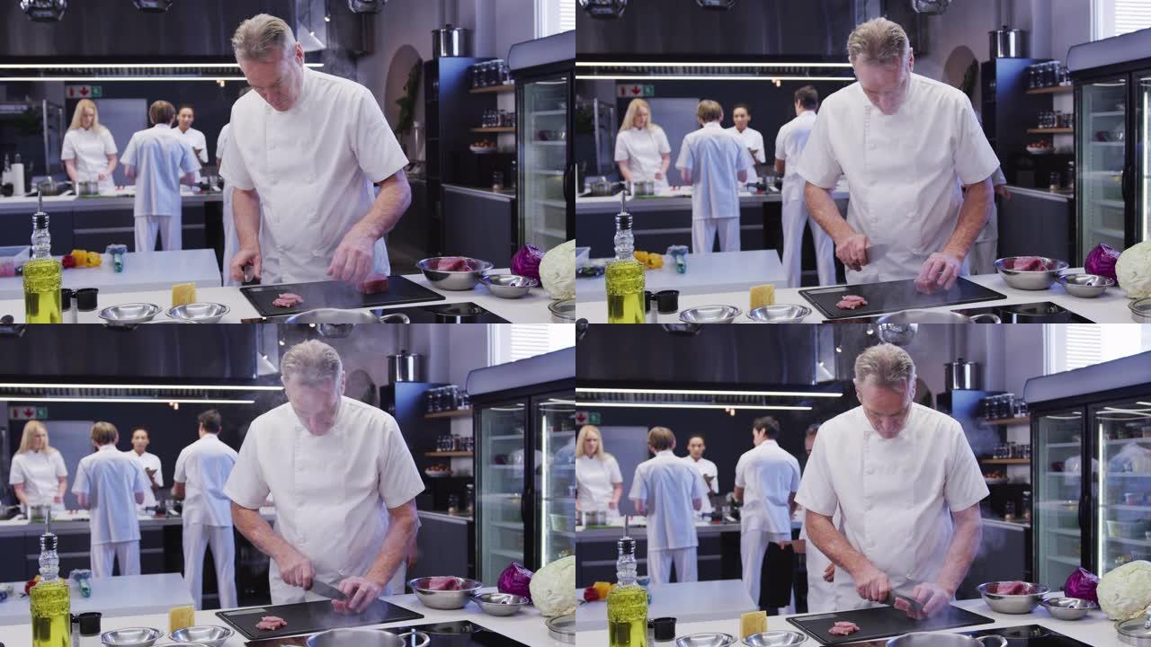 专业的白人男厨师在餐厅厨房里穿着白色的厨师，将肉切成薄片