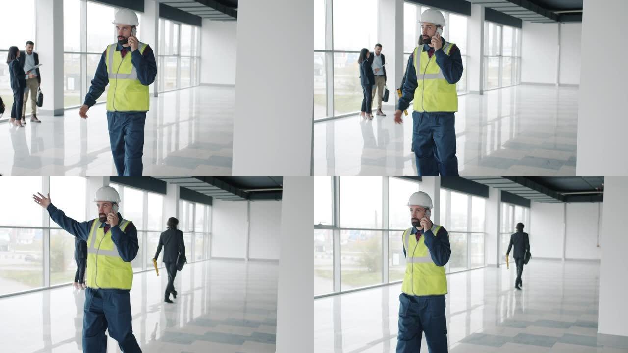 在新办公中心的室内，严肃的年轻建筑商穿着制服在手机上聊天