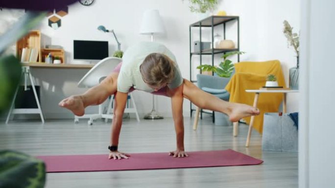 女瑜伽学生在家锻炼，在垫子上做手臂平衡体式