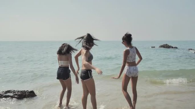 亚洲三个十几岁的女孩在夏天的海滩上玩耍，展示自由。东南亚和东亚: 海滩上的乐趣概念。