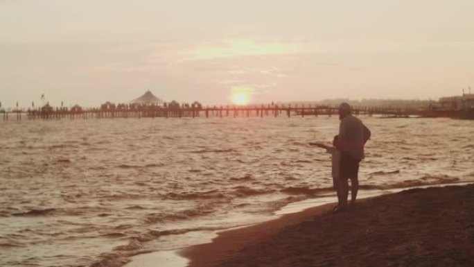 爸爸和小儿子在度假时在海边观看史诗般的夏日日落景色的电影拍摄。团结概念。