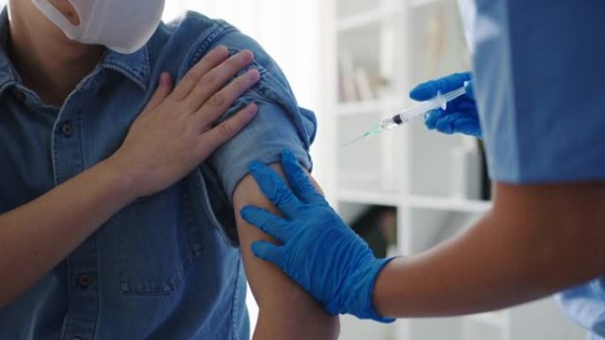 年轻的亚洲女护士给新型冠状病毒肺炎或流感抗病毒疫苗注射给高级男性患者戴上口罩，防止健康诊所的病毒疾病