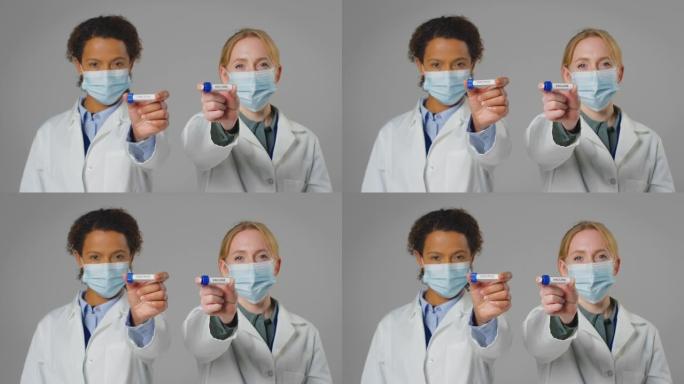 工作室拍摄的实验室研究人员戴着口罩，手里拿着标有欧米克隆和疫苗的试管