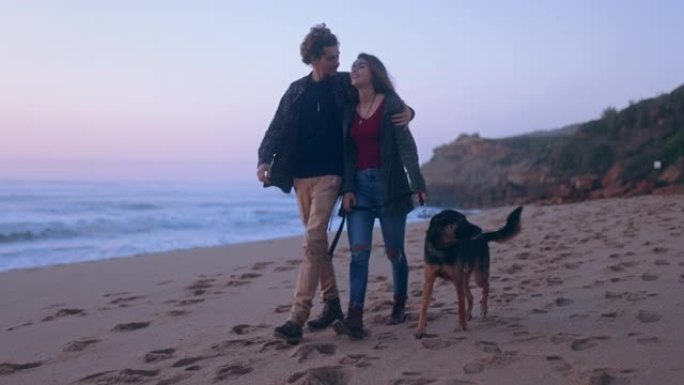 男女朋友在海滩上拴皮带遛狗