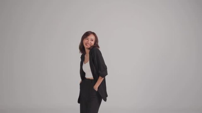 亚洲中国美女站在口袋里微笑与灰色背景工作室拍摄