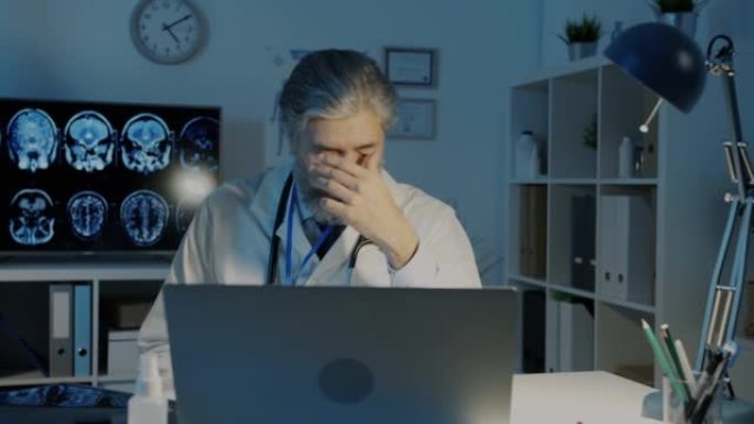 疲倦的医生检查MRI肺部图像脱下眼镜在黑暗的办公室中感到疲惫