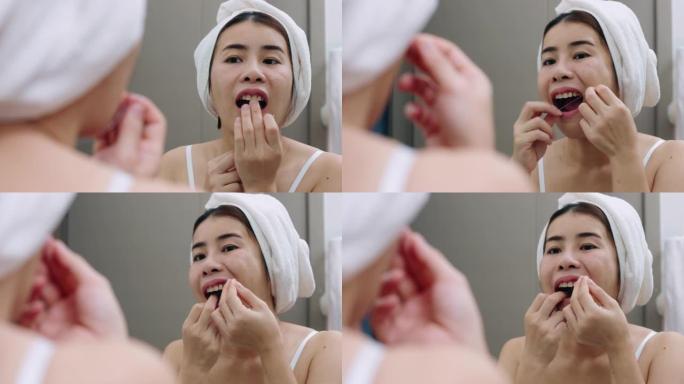 亚洲妇女在家里的浴室里用牙线洁牙