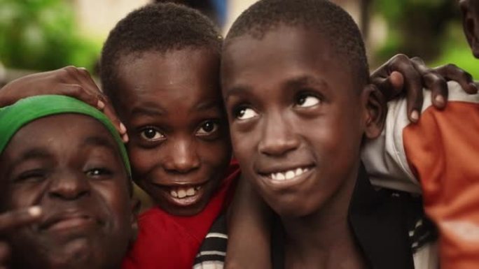 特写一群非洲农村小男孩的脸，笑着，笑着，对着镜头摆姿势。一群富有表现力的黑人男性朋友享受他们的童年，