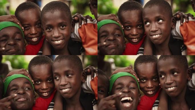 特写一群非洲农村小男孩的脸，笑着，笑着，对着镜头摆姿势。一群富有表现力的黑人男性朋友享受他们的童年，