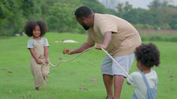一个黑人女儿的父亲和儿子正在公园里玩拖船。在快乐的锻炼和共度时光中，每个人的脸都容颜。