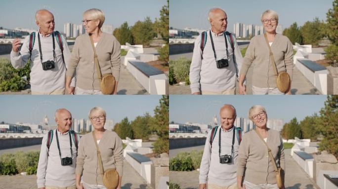 多莉拍摄快乐的游客爱的老年夫妇在夏天牵着手在城市散步