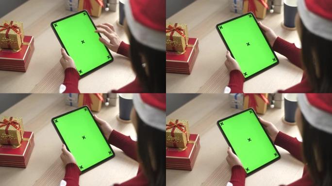 女人在圣诞节使用带有绿屏的数字平板电脑