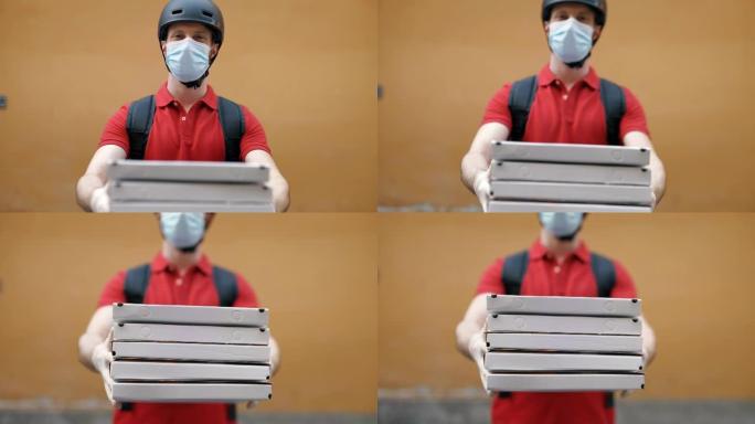 一位年轻的披萨送货快递员的肖像，戴着防护口罩和手套，对他在相机中的工作感到满意。快递，送货上门，电子
