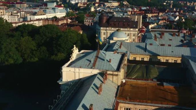 夏季日出时，无人机在利沃夫古城的历史建筑上方移动，靠近乌克兰光荣的国旗。