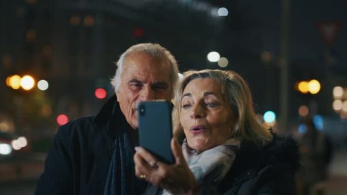 晚上，一对幸福的高级夫妇正在市中心用智能手机进行自拍或视频通话。