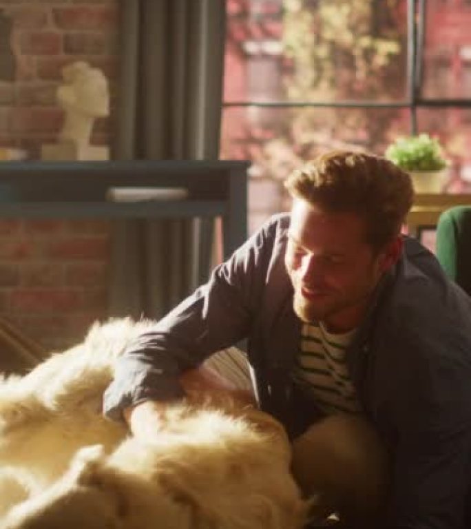 垂直屏幕: 年轻的成年男子在客厅地板上玩乐并与他的金毛猎犬宠物玩耍。狗主人在家抚摸、抓挠和戏弄他的犬