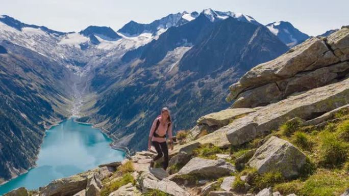 年轻的女徒步旅行者在风景秀丽的群山中上山行走