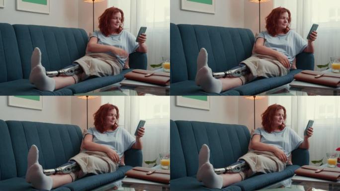 快乐美丽的成功女人，未来仿生假肢使用智能手机在家里的沙发上网上购物。