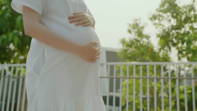 孕妇在户外爱抚腹部。母性