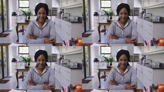 肖像，漂亮年轻的黑人千禧一代非洲女人，看着相机，双臂交叉，微笑，自信，专业，在家工作