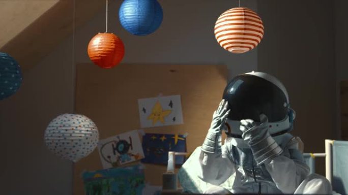 太空旅行梦想。小男孩在太空主题房间的床上醒来，打开头盔遮阳板看太阳光。