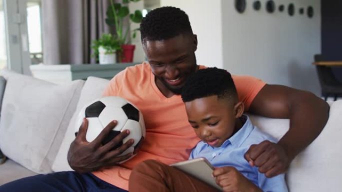 非裔美国人父子在家里用数字平板电脑观看体育节目时一起欢呼