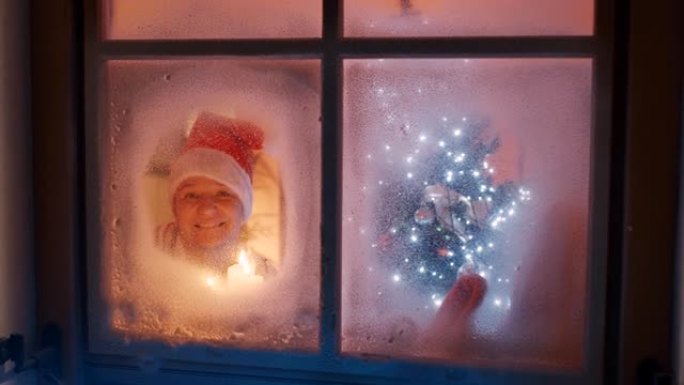 SLO MO Happy woman在圣诞节之夜透过窗户向镜头挥手