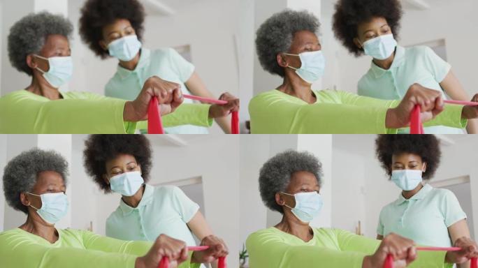 非裔美国女理疗师戴口罩协助资深女病人运动