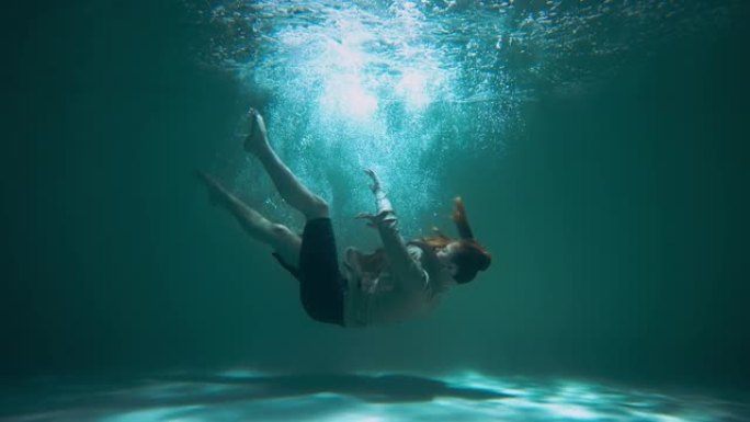 抑郁症侧视年轻疲惫的女人穿着西装，闭着眼睛在水下下沉，打底部慢动作。