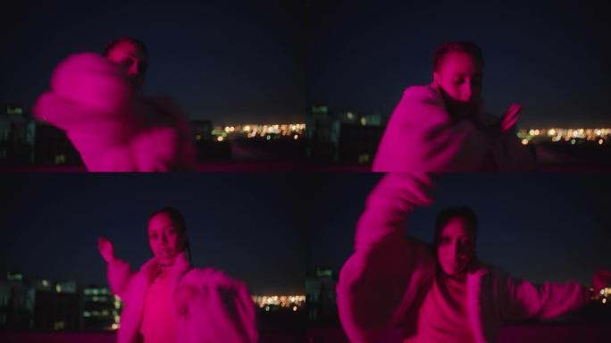 快乐的女人在屋顶上跳舞顶女孩表演嘻哈舞蹈风格在夜晚红光的城市里玩得开心自由式舞者