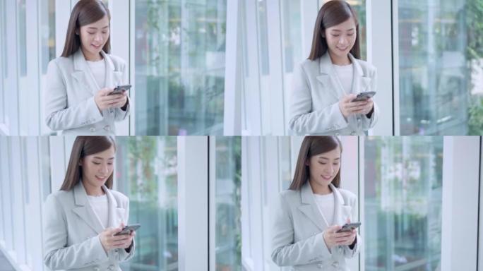亚洲女商人在现代办公楼中行走和使用智能手机
