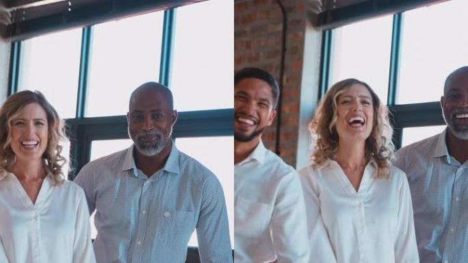 微笑的多元文化商业团队在现代办公室中站在一起的肖像