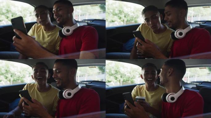 两个快乐的混血朋友拿着咖啡，在出租车上使用智能手机