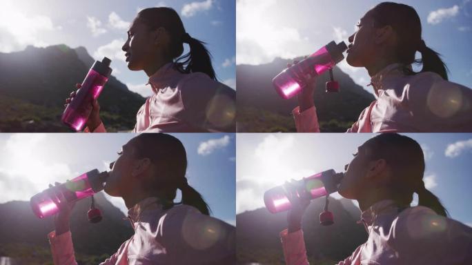 非裔美国妇女在山上徒步旅行时从瓶子里喝水