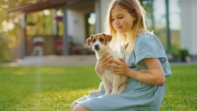 可爱的女孩在户外草坪上野餐时，抱着她最喜欢的血统狗朋友。她抚摸和拥抱她的小杰克罗素梗。田园诗般的避暑