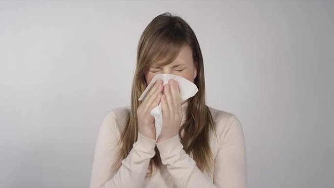 生病的女人用纸巾吹鼻子