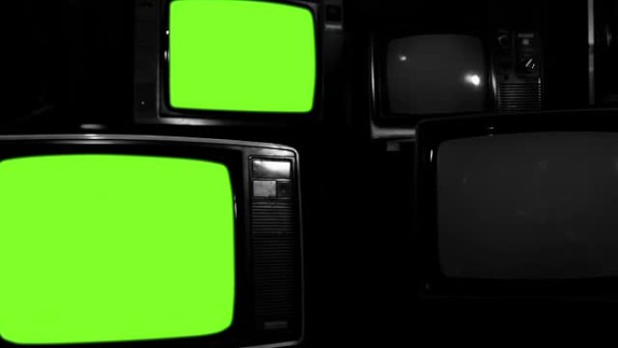 四台旧电视在黑暗的房间里打开绿色屏幕。放大。黑白色调。4k分辨率。
