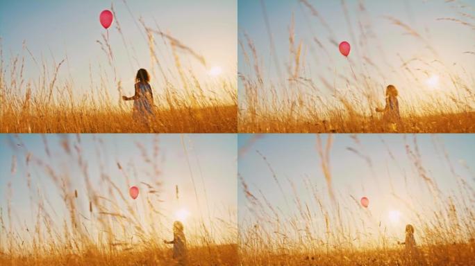 带着红色气球的SLO MO小女孩在黄金时段在草地上行走