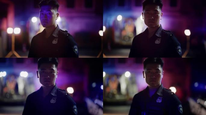 中景:在警笛的灯光下，一名年轻的亚洲男警察看着别处，然后转向相机。勇敢的法律官员，保护公民和平民的安
