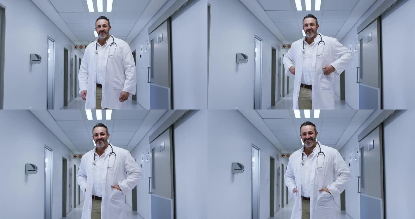 微笑的白人男性医生的肖像穿着实验室外套站在医院走廊上