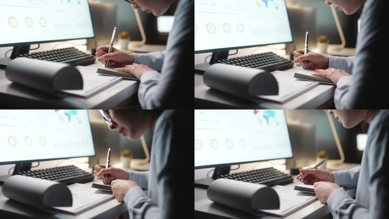 亚洲女商人做笔记，晚上在办公室用电脑工作，聚焦概念