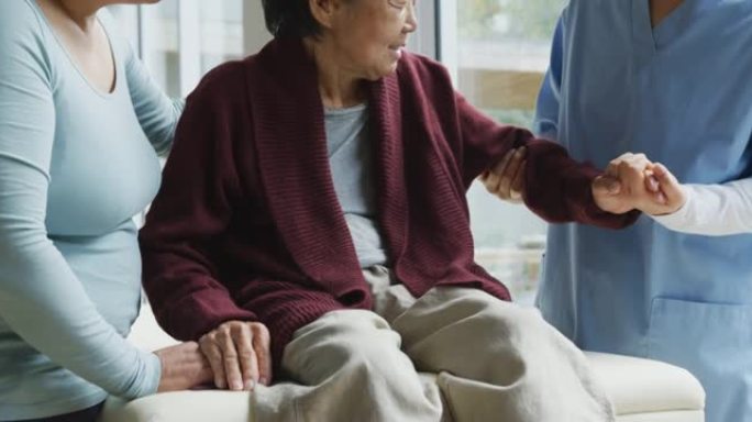亚洲女性理疗师治疗老年女性患者的手臂，并在手术中与成年女儿